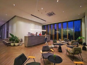 A modern reception area with a counter, seating, and large windows. - M2 Hotel Waterside (Phayao)