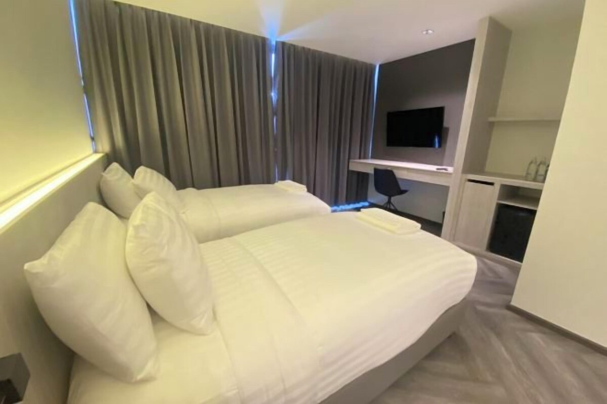 A modern hotel room with a large bed, a desk, and a flat-screen TV mounted on the wall.