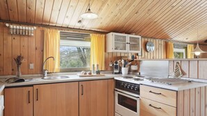 A kitchen with wooden cabinets, a stove, and a window with yellow curtains.