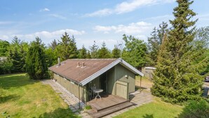 A small, single-story wooden shed with a sloped roof, a small porch, and a window.