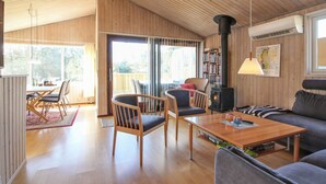Ein gemütliches Blockhaus-Interieur mit Holzbalkendecke, Kamin, einer Couch und einem Essbereich.