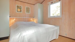 Ein Schlafzimmer mit Holzwänden, einem Bett, einem Fenster und zwei Wandleuchten.