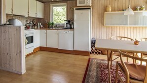 Eine Küche mit Holzausstattung, einer Mikrowelle, einem Kühlschrank und einem Essbereich mit Tisch und Stühlen.