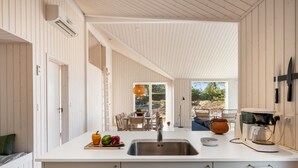 Une cuisine moderne dotée d’un grand îlot central, d’un évier et d’un coin repas offrant une vue agréable.