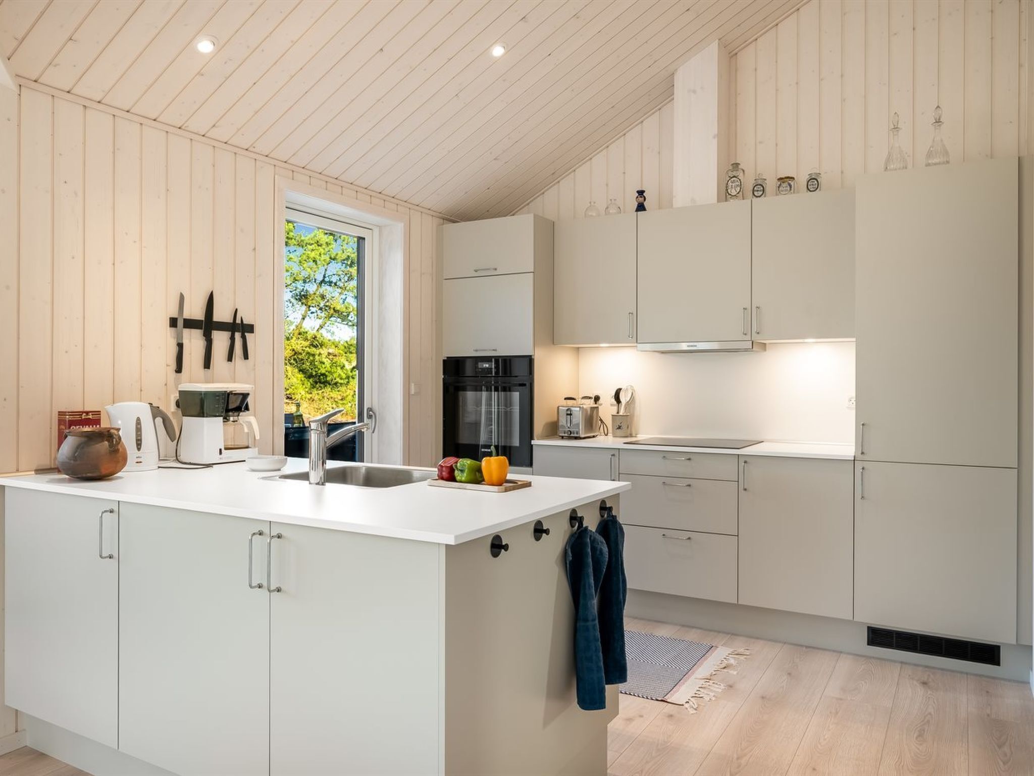 A modern kitchen with a central island, white cabinetry, and a window providing natural light.