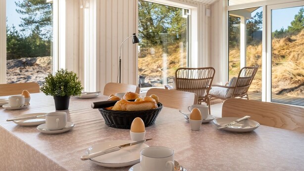 Une table dressée pour le petit-déjeuner, avec des chaises et une vue sur l’extérieur.
