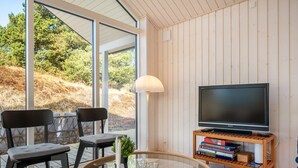 Un salon moderne avec un téléviseur, des livres et une table basse en verre.