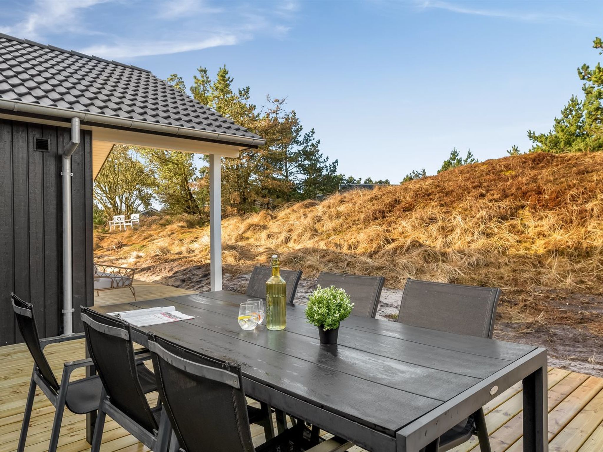 Un patio al aire libre con una mesa, sillas, una pérgola y vistas a una colina.