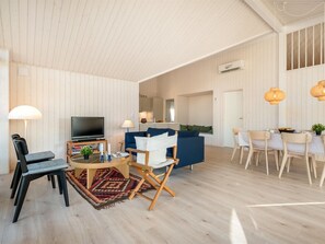 Ein geräumiger Wohnbereich mit Fernseher, blauem Sofa, Esstisch und Stühlen.