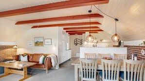 A cozy loft-style living space with a dining area, wooden beams, a kitchen, and a loft bed. - "Görel" - 1km from the sea by Interhome (Blåvand)