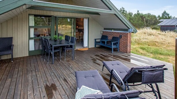 A modern house with a wooden deck, a dining area, and a patio with lounge chairs. - "Görel" - 1km from the sea by Interhome (Blåvand)