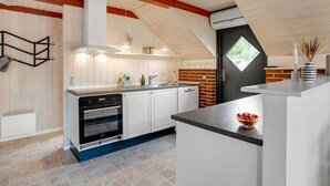 A modern kitchen with white cabinets, a black oven, and a brick accent wall. - "Görel" - 1km from the sea by Interhome (Blåvand)