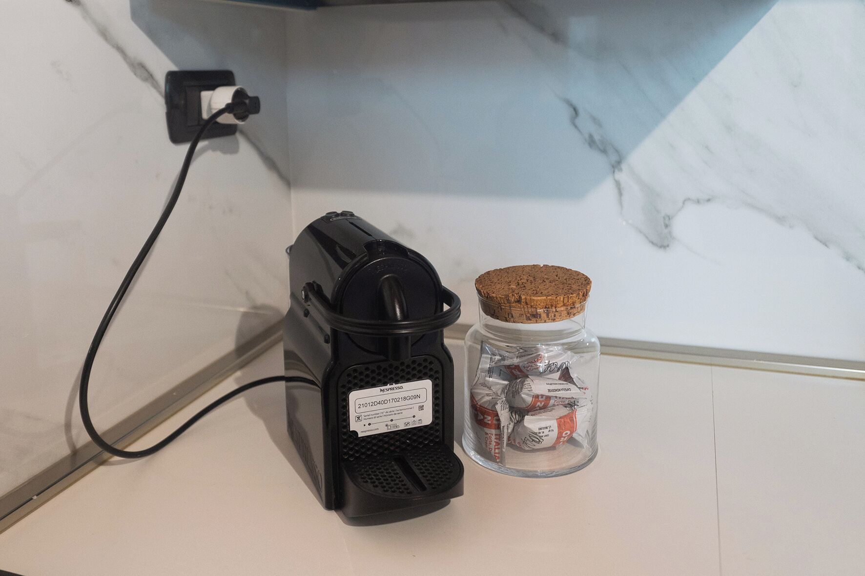 A Nespresso coffee machine and a jar of coffee capsules on a countertop.