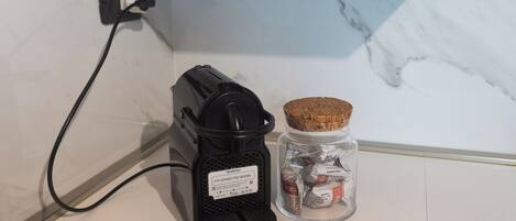 A Nespresso coffee machine and a jar of coffee capsules on a countertop.