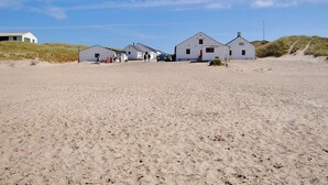 A row of white buildings with a sandy beach in the foreground.