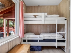 A bunk bed room with wooden walls, a window, and a bench.