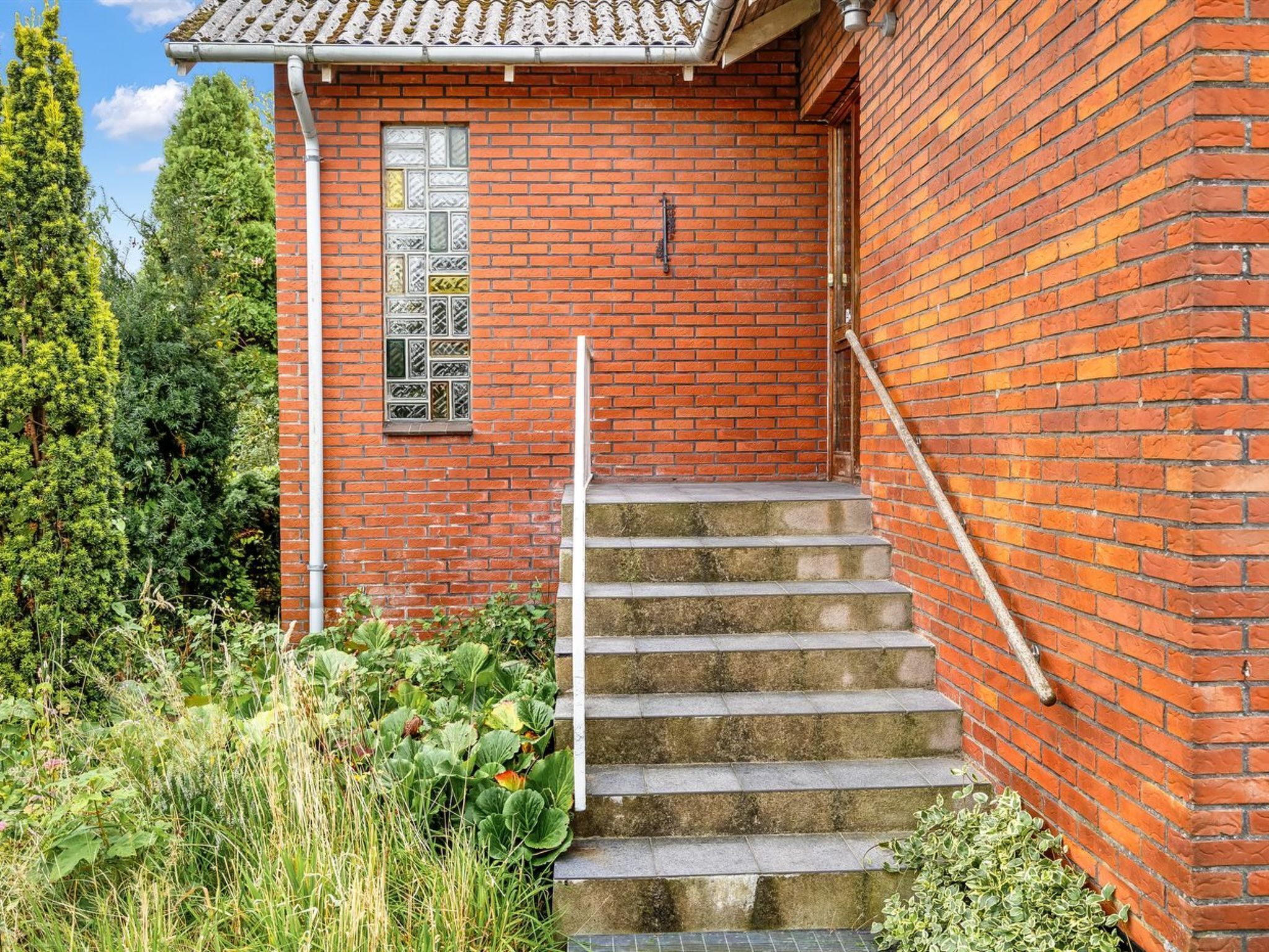 Ein Backsteinhaus mit einem kleinen Fenster und einer Treppe aus Stein, die zu einer Tür führt.
