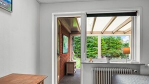 A bedroom with a wooden desk, a radiator, and a window with a view of greenery.