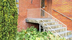 A brick building with a wooden door, white railings, and a concrete staircase.