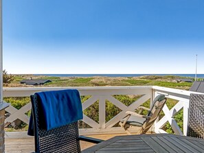 A wooden deck with a view of the ocean and dunes.