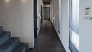 A modern hallway with a staircase on the left, recessed lighting, and large windows on the right. - Minimal brand new villa with private pool close to Athens (Kalamos)