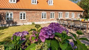 A brick building with a red-tiled roof, multiple windows, and a garden with purple hydrangea flowers. - "Myra" - 18km from the sea by Interhome (Bredebro)