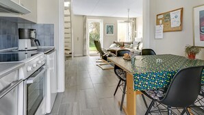 A modern kitchen with a stove, coffee maker, and a dining area with a patterned table and chairs.