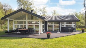 Une maison moderne dotée d’un patio couvert, de grandes fenêtres et d’une terrasse.