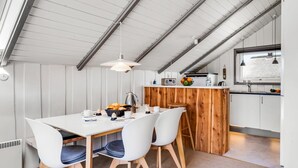 A modern kitchen with a wooden island, white cabinetry, and a dining area with two chairs. - "Halda" - 300m from the sea by Interhome (Vejers Strand)