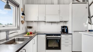 A modern kitchen with white cabinets, a stainless steel sink, a built-in oven, and a coffee maker. - "Halda" - 300m from the sea by Interhome (Vejers Strand)