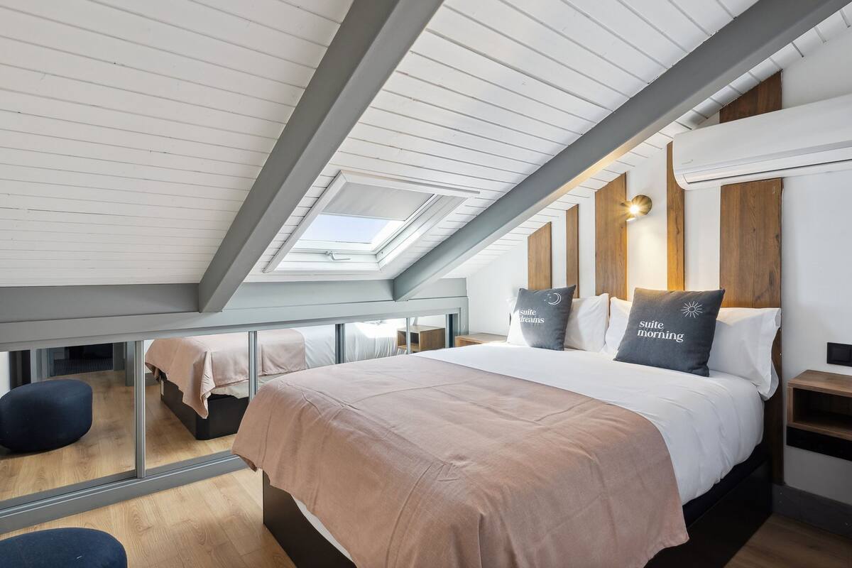 Ein modernes Hotelzimmer mit einem großen Bett, einem Dachfenster und Blick auf die Stadt.