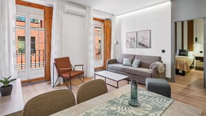 Ein modernes Wohnzimmer mit Sofa, Sesseln, einem Couchtisch und einem Essbereich.