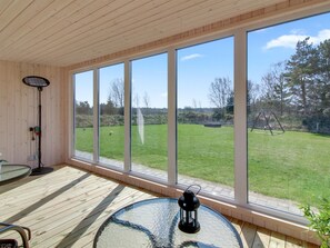 A room with large windows, a wooden ceiling, a round glass table with a lantern, and a floor lamp. - "Ethel" - 1.5km to the fjord by Interhome (Blåvand)