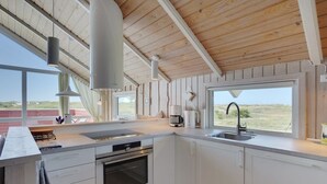 A modern kitchen with a large window, wooden ceiling, and white cabinetry. - "Betti" - 300m from the sea by Interhome (Rømø)