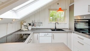 Una cocina moderna con tragaluz, horno empotrado y ventana con vistas al verdor.