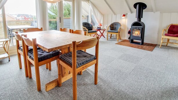 Una habitación acogedora con una mesa y sillas de madera, chimenea y ventanas grandes.