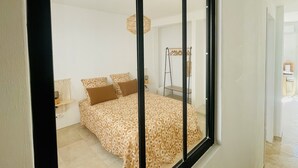 A bedroom with a bed, pillows, a hanging light fixture, and a wooden ladder shelf.