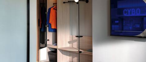 A modern room with a wardrobe, a wall-mounted TV displaying 'CYBO', and a floor lamp.
