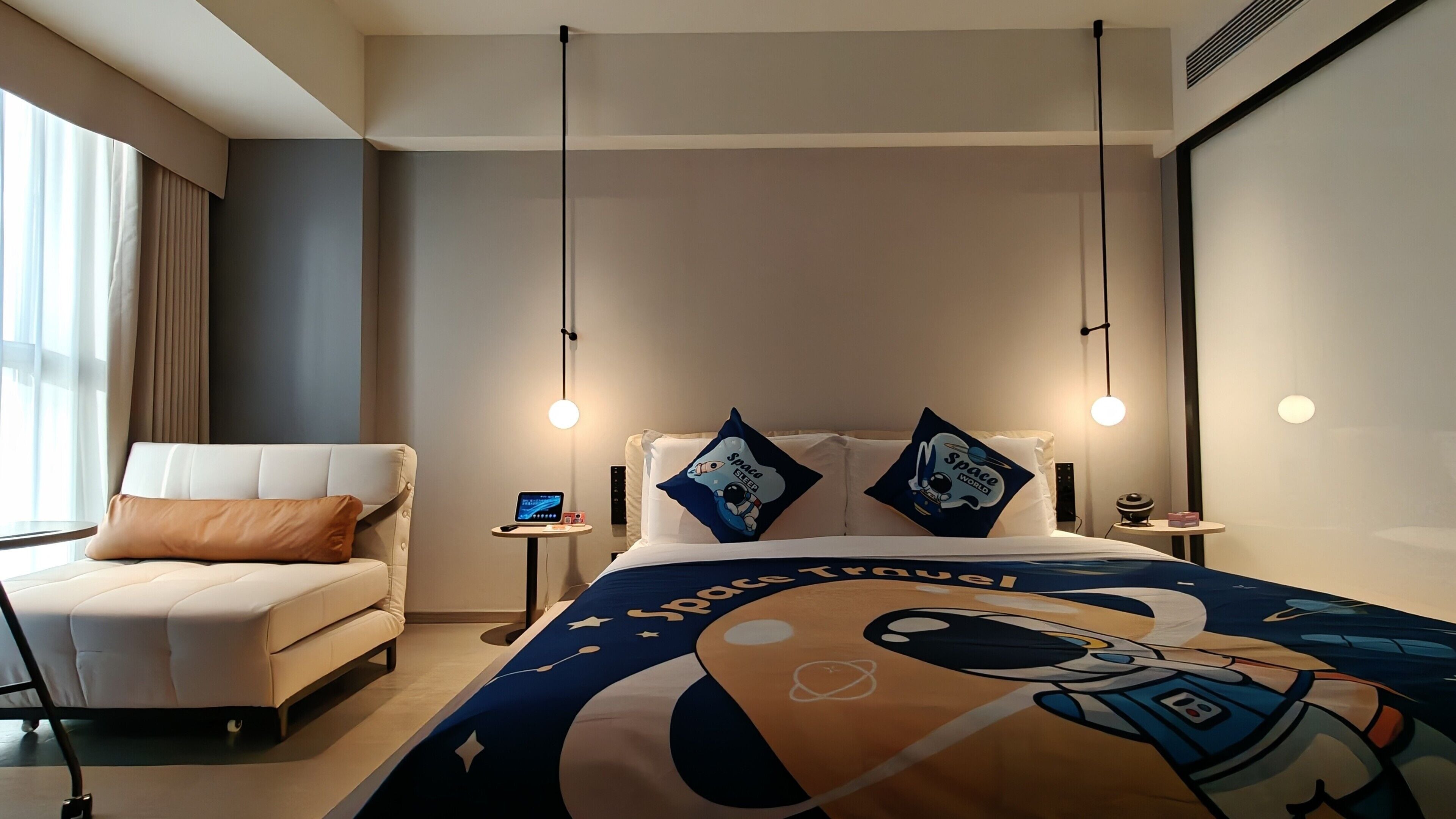 A modern hotel room with a large bed, a chair, and a small table.