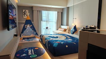 Una habitación de hotel con una colcha de tema espacial, una decoración tipo tienda de campaña y un televisor montado en la pared que muestra una interfaz con temática espacial.