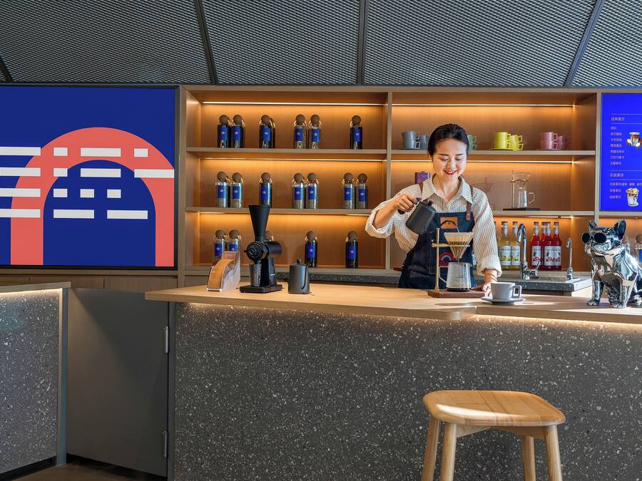 A bar area with a counter, shelves with bottles, and a menu board.