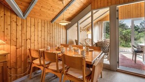 Un interior de madera con una mesa de comedor preparada para cuatro personas, rodeada de sillas.