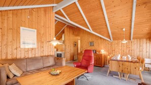 Un interior de madera acogedor con un sofá, una mesa de comedor y una silla roja.