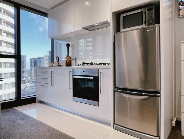 Enjoy cooking in this well-equipped kitchen with a refrigerator, oven, and white cabinetry.