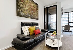 Relax in this stylish living room with a comfortable sofa, glass coffee table, and a large window offering a city view.