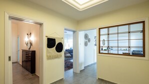 A hallway with a modern kitchen visible through a frosted glass window, a dark wooden cabinet, and a hanging towel. - Eclectic Rabin Square Apt by Sea N' Rent (Tel Aviv)