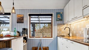 A modern kitchen with a large window, wooden cabinets, and a wooden bench.