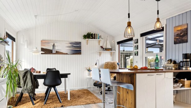 A modern kitchen with a central island, bar stools, and pendant lighting.