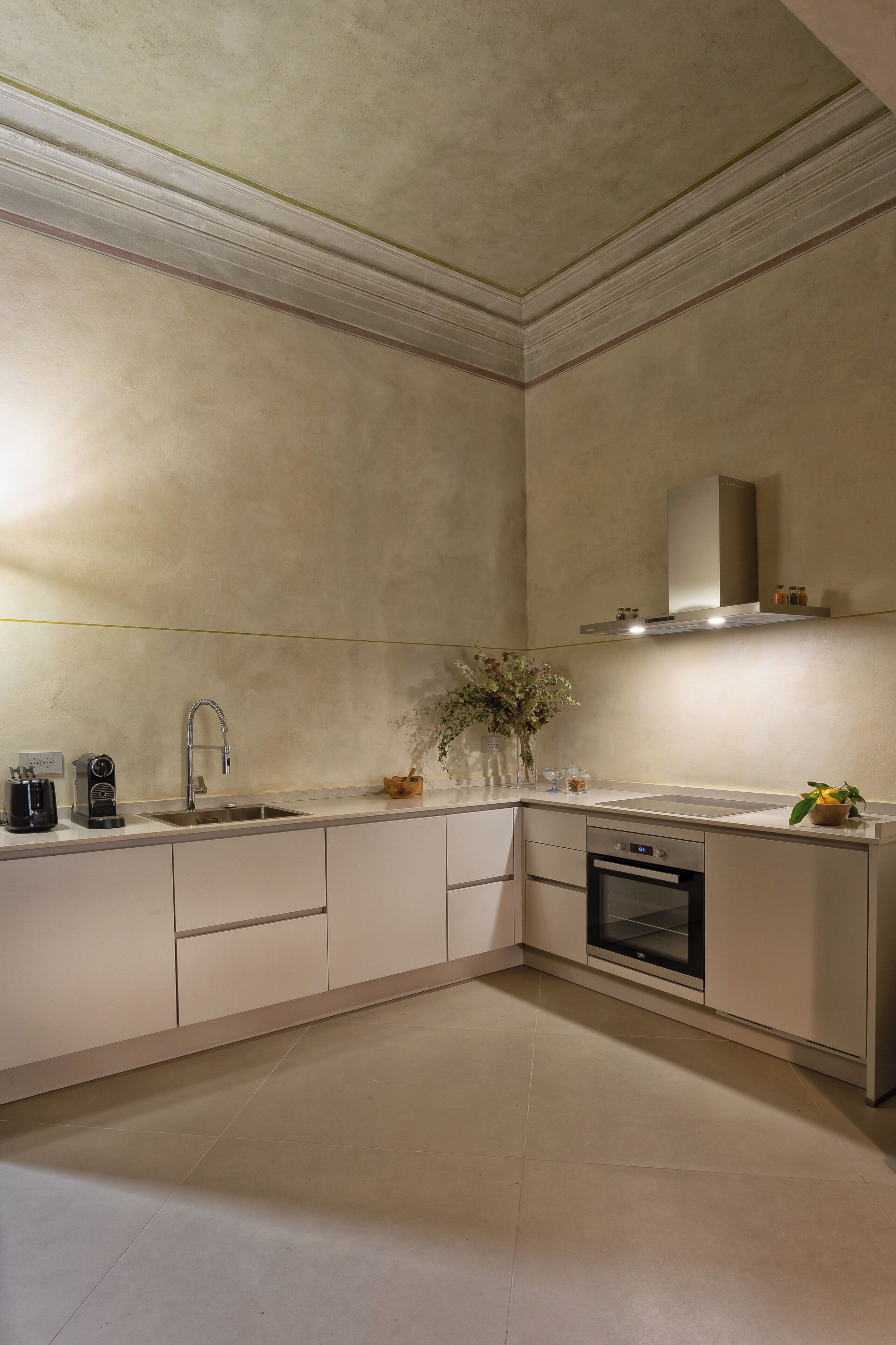Una cucina moderna con forno integrato, lavello in acciaio inossidabile e cappa aspirante.