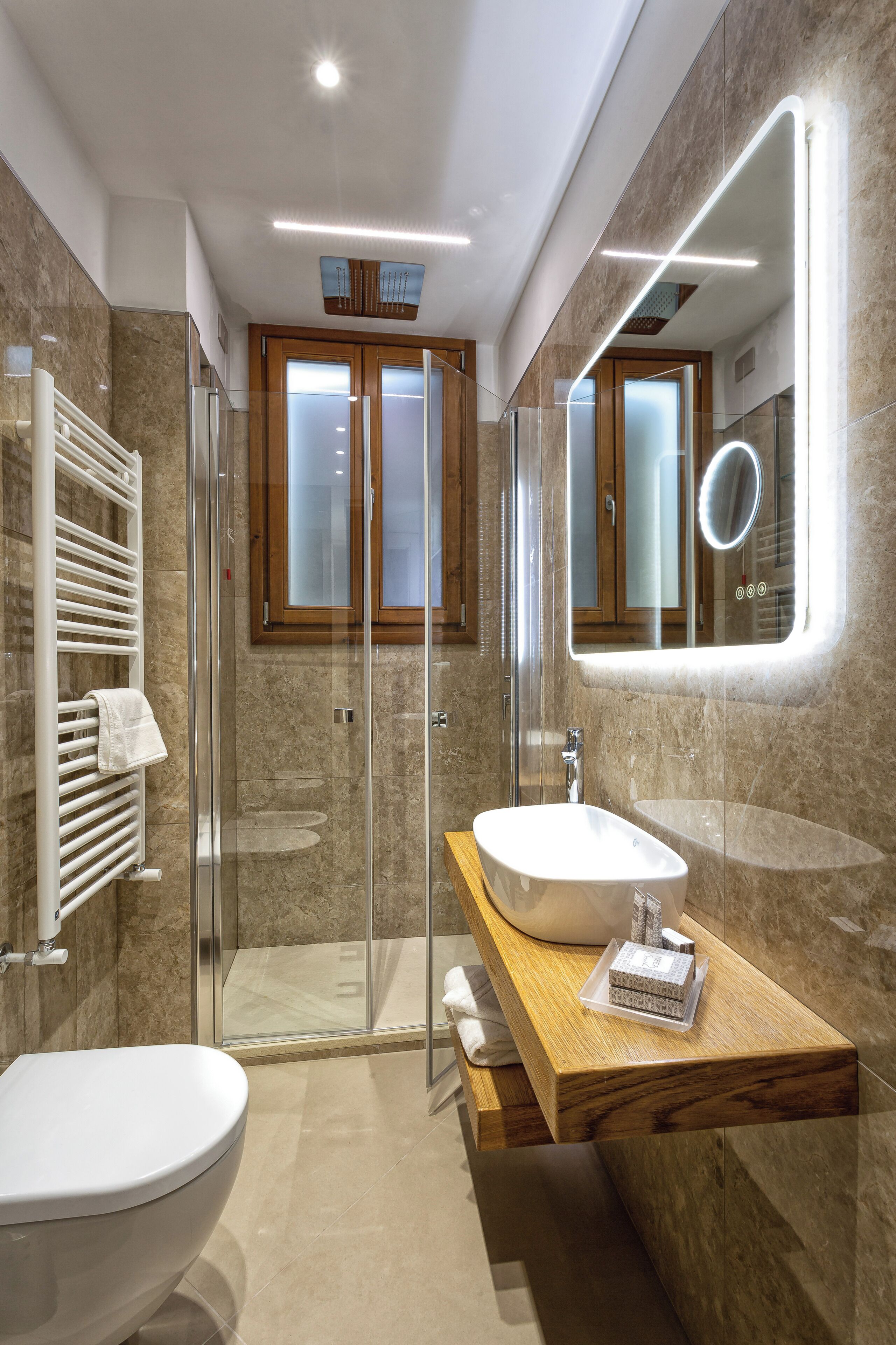 A modern bathroom with a glass shower enclosure, a white sink, and a wooden vanity.